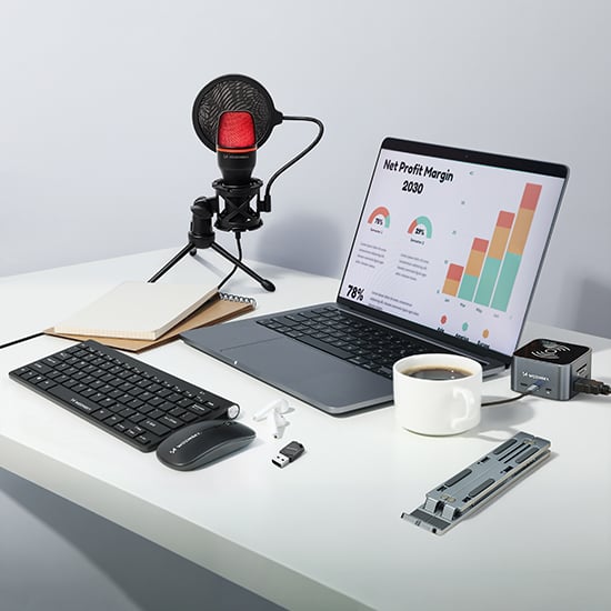 Wozinsky computertilbehør med tastatur, mus, mikrofon, laptop-stander og kaffekop på lyst skrivebord